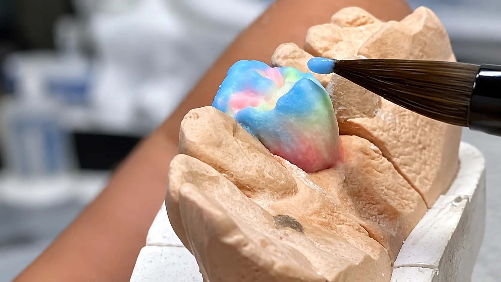Aplicação de cerâmica colorida com pincel sobre coping em modelo de gesso