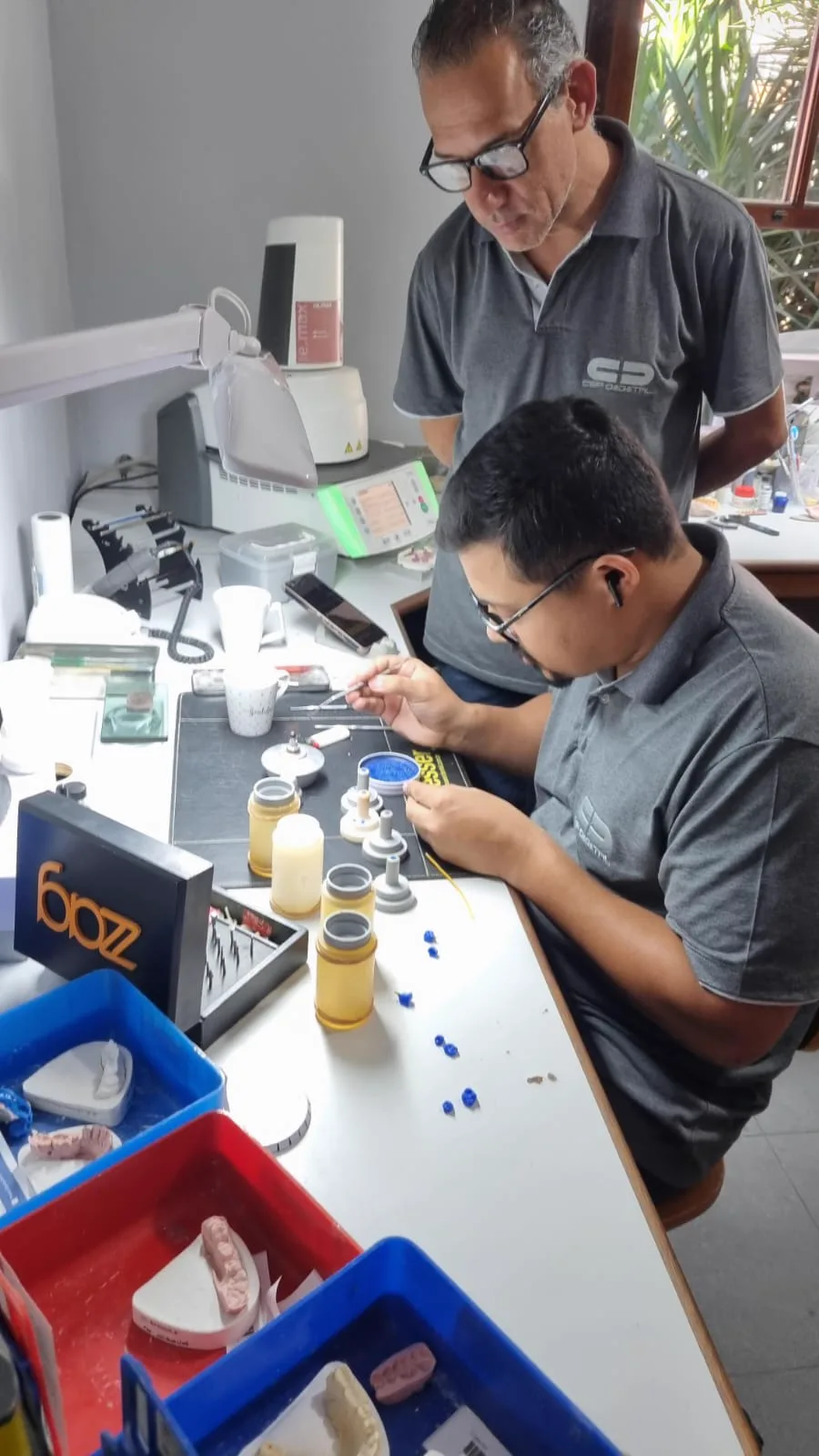Técnicos revisando e finalizando trabalhos na bancada do laboratório